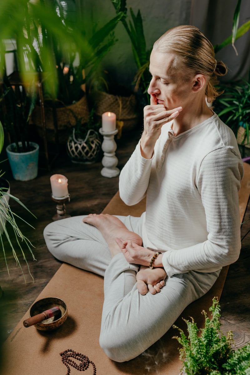 Young man practicing Surya Bhedana Pranayama block the left nostril with the ring finger sitting in Lotus pose